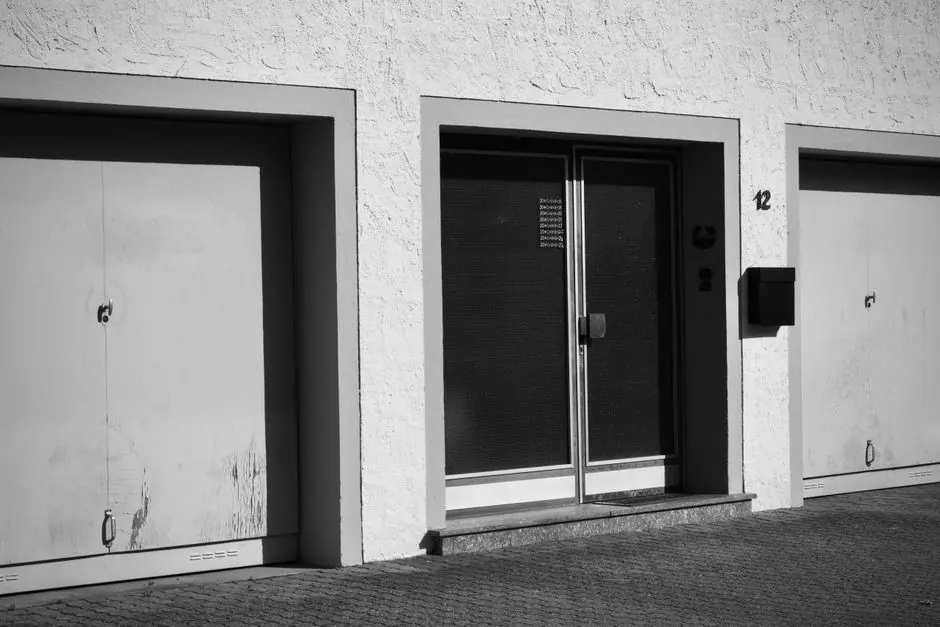 Monochrome photo of an urban building facade with garages and doors.