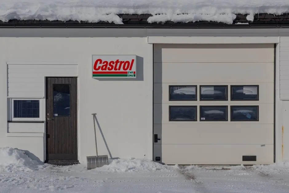 Snowy garage entrance featuring a Castrol sign and shovel.
